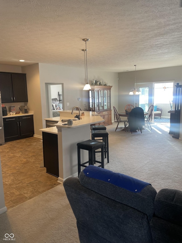 kitchen with hanging light fixtures, a breakfast bar area, light colored carpet, and an island with sink