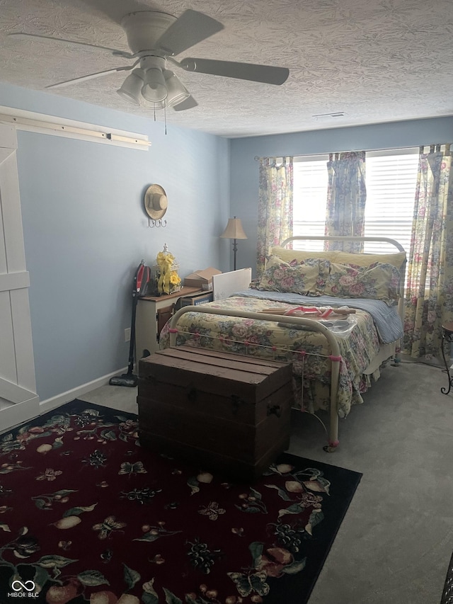 carpeted bedroom with ceiling fan and a textured ceiling