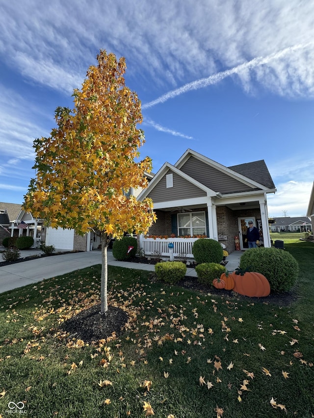 view of front of property featuring a garage, covered porch, and a front yard