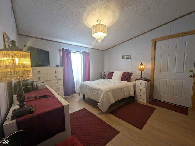 bedroom featuring crown molding, lofted ceiling, a textured ceiling, and light hardwood / wood-style floors