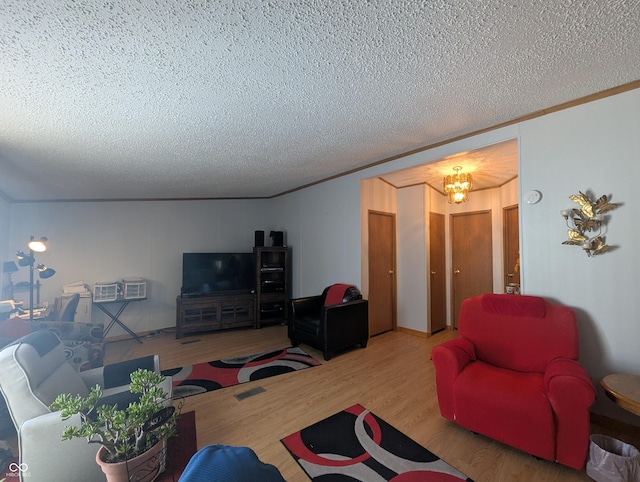 living room with hardwood / wood-style floors, a notable chandelier, ornamental molding, and a textured ceiling