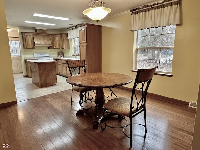 dining area featuring sink, ornamental molding, and light hardwood / wood-style floors