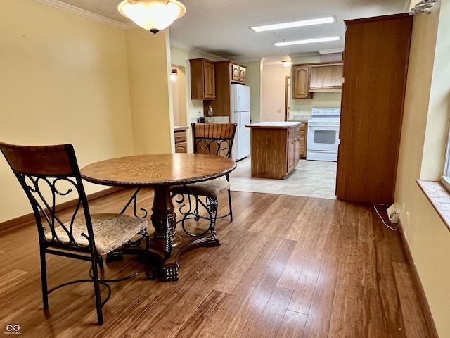 dining space with baseboards, wood finished floors, and crown molding