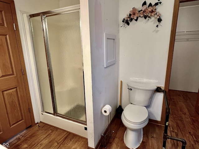 bathroom featuring wood-type flooring, toilet, and a shower with door