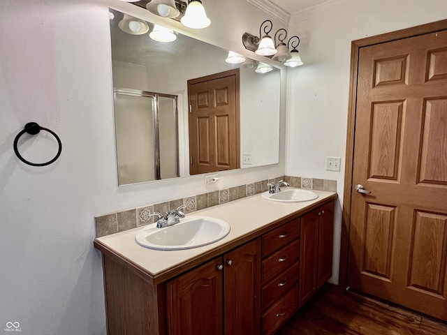 full bath featuring double vanity, ornamental molding, a stall shower, and a sink