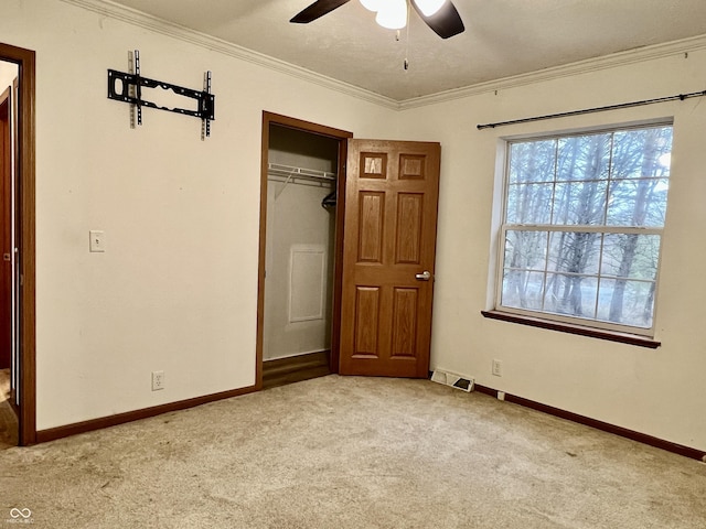 unfurnished bedroom with crown molding, light carpet, ceiling fan, and a closet