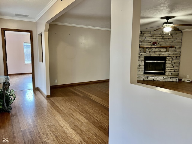 interior space featuring visible vents, crown molding, baseboards, wood finished floors, and a ceiling fan