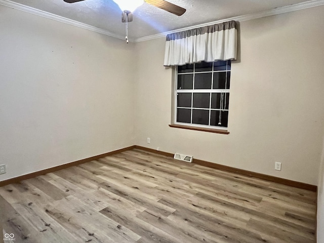 unfurnished room with crown molding, wood finished floors, visible vents, and baseboards