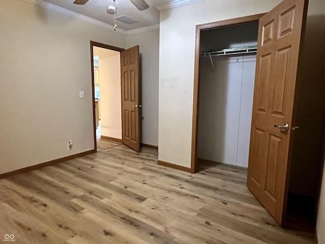 unfurnished bedroom with crown molding, baseboards, light wood-type flooring, and a closet