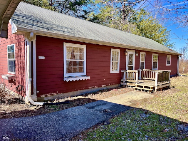 ranch-style house with a wooden deck and roof with shingles