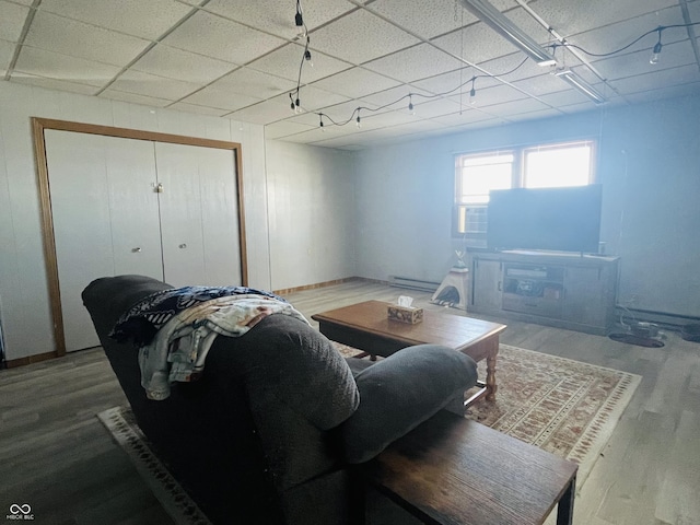 living room featuring a drop ceiling, a baseboard heating unit, and hardwood / wood-style floors