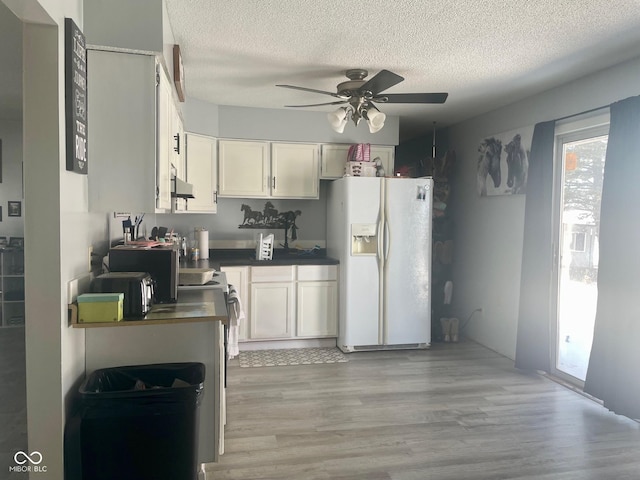 kitchen featuring light hardwood / wood-style flooring, ceiling fan, white fridge with ice dispenser, and white cabinets