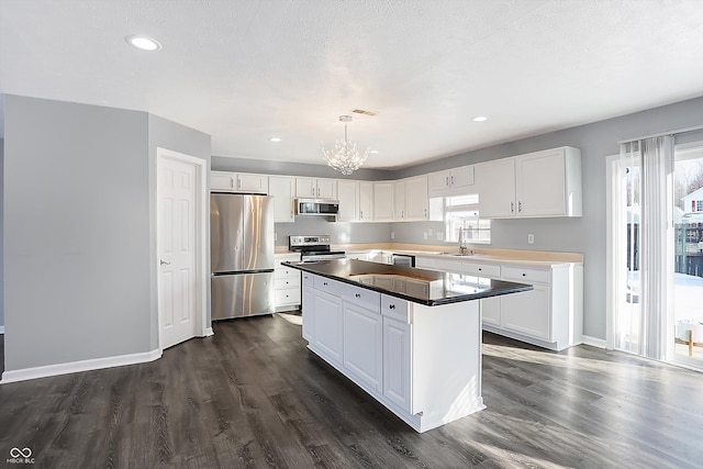 kitchen featuring stainless steel appliances, pendant lighting, white cabinets, and sink