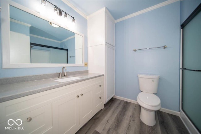 bathroom featuring hardwood / wood-style floors, vanity, toilet, walk in shower, and ornamental molding