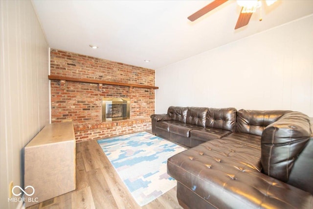 living room with a wood stove, light hardwood / wood-style floors, wood walls, and ceiling fan