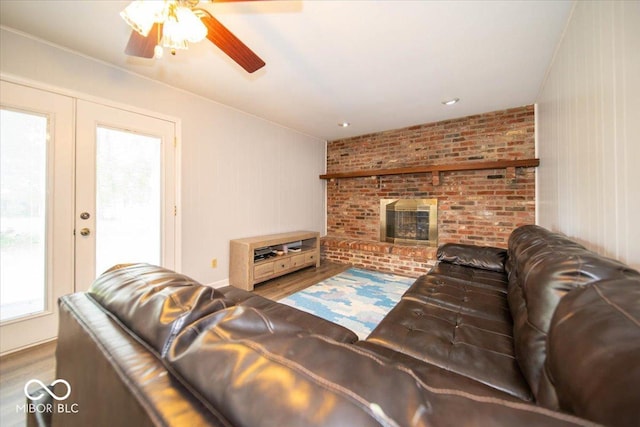 living room with ceiling fan, a fireplace, a wealth of natural light, and light wood-type flooring