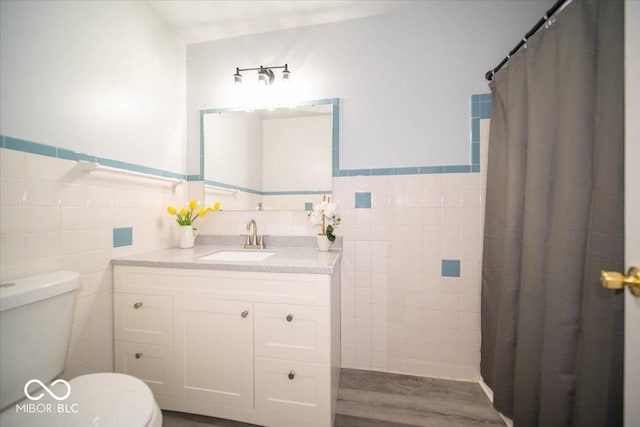 bathroom featuring toilet, hardwood / wood-style floors, a shower with shower curtain, tile walls, and vanity