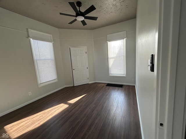 unfurnished room with ceiling fan, a textured ceiling, and dark hardwood / wood-style flooring