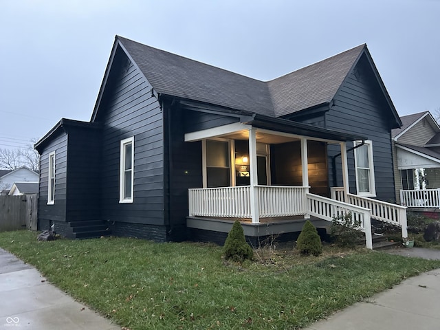 view of side of home featuring a lawn and covered porch