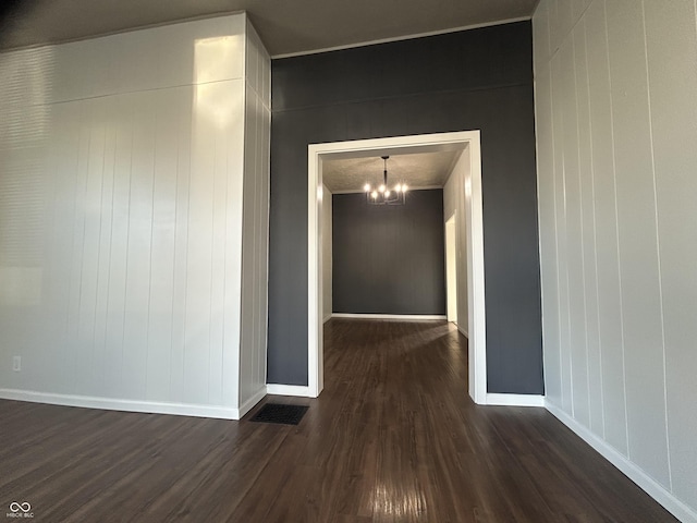 corridor with an inviting chandelier and dark hardwood / wood-style floors