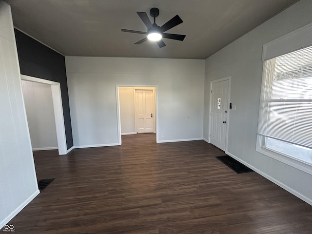 empty room with dark hardwood / wood-style floors, a wealth of natural light, and ceiling fan