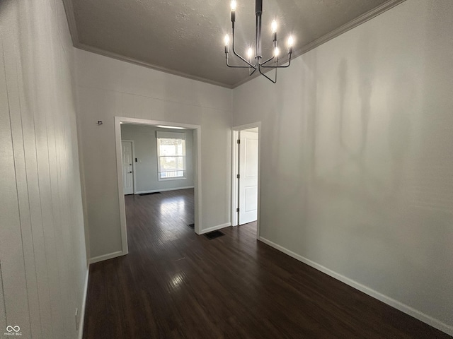 unfurnished dining area with crown molding, dark hardwood / wood-style flooring, a textured ceiling, and a notable chandelier