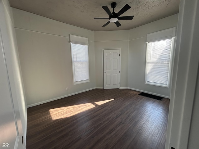 empty room featuring ceiling fan, dark hardwood / wood-style flooring, and a textured ceiling