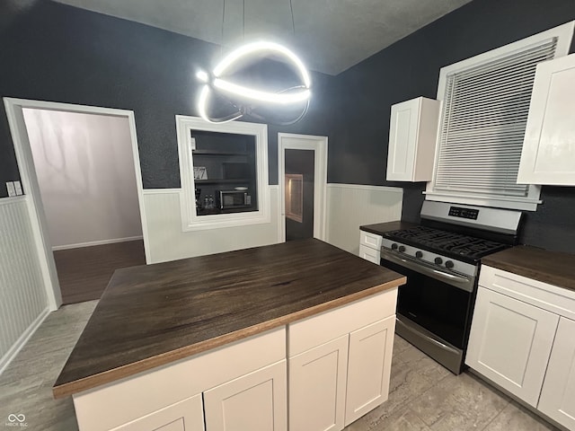 kitchen with white cabinetry, wooden counters, stainless steel range with gas stovetop, and black microwave