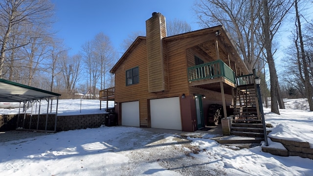 snow covered house featuring a garage and a wooden deck