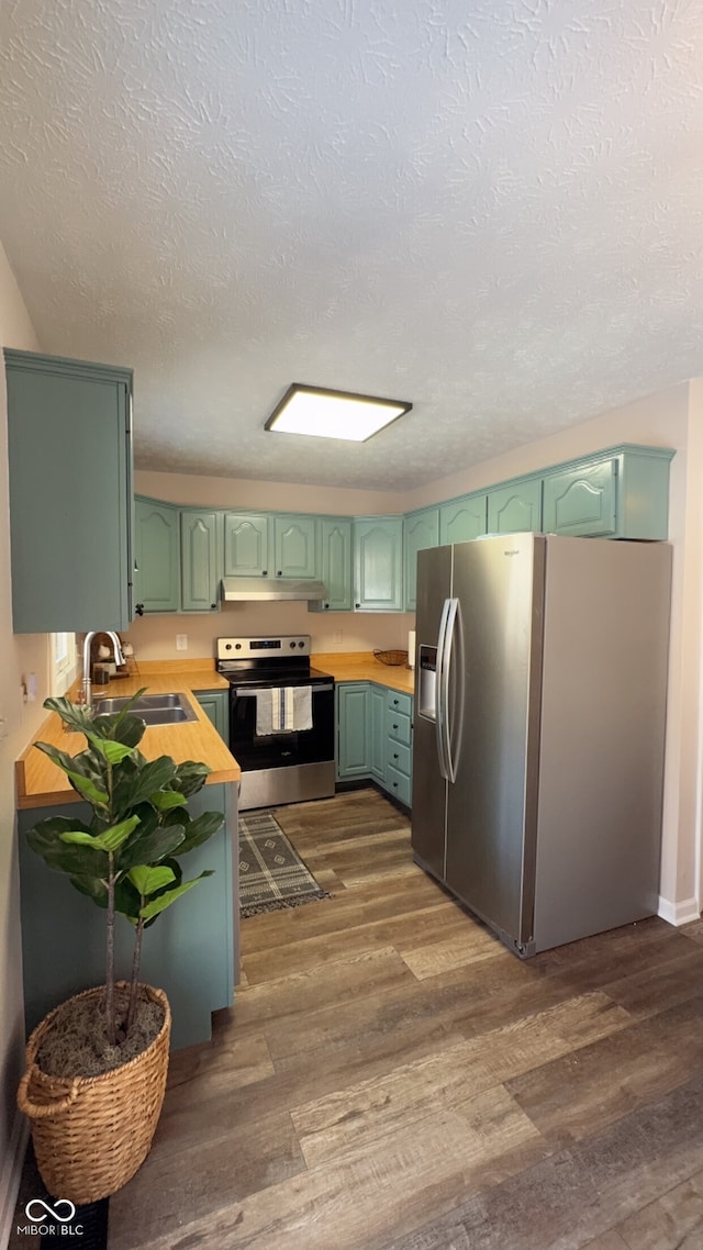 kitchen featuring sink, green cabinets, stainless steel appliances, a textured ceiling, and dark hardwood / wood-style flooring