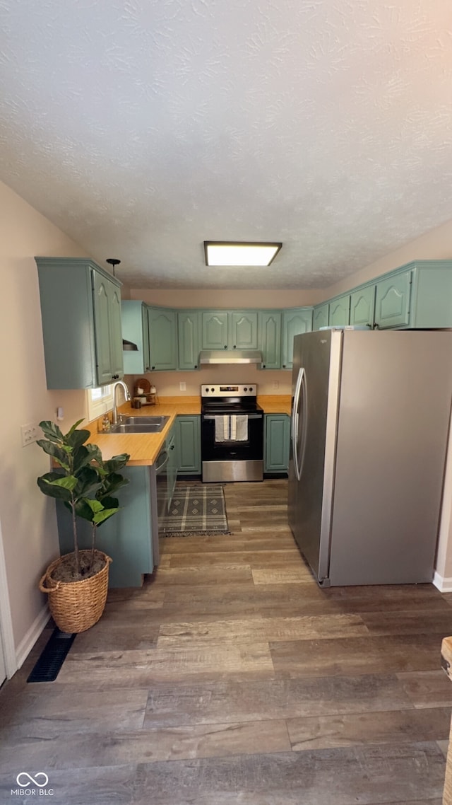 kitchen with sink, green cabinets, kitchen peninsula, stainless steel appliances, and dark wood-type flooring