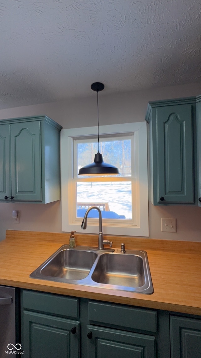 kitchen featuring pendant lighting, black dishwasher, sink, and a textured ceiling