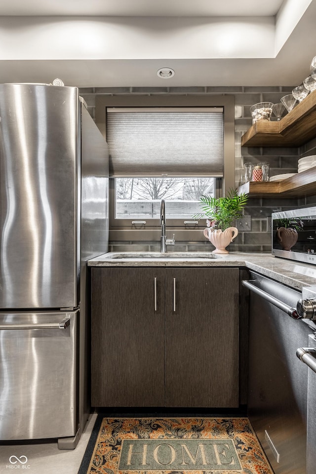 kitchen with a sink, stainless steel appliances, dark brown cabinetry, and light countertops