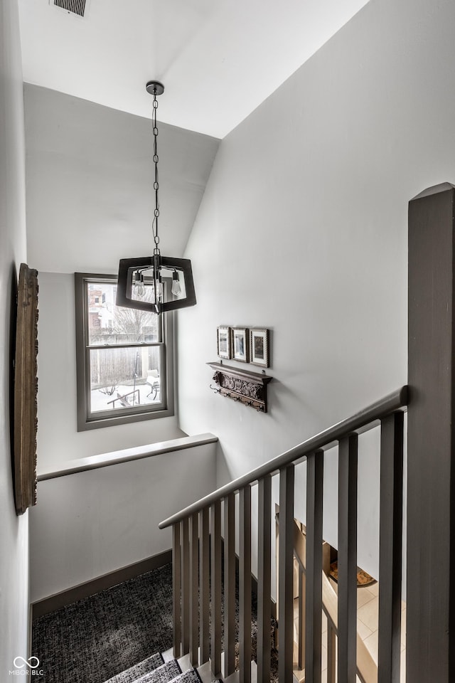 stairs with arched walkways, visible vents, baseboards, and vaulted ceiling