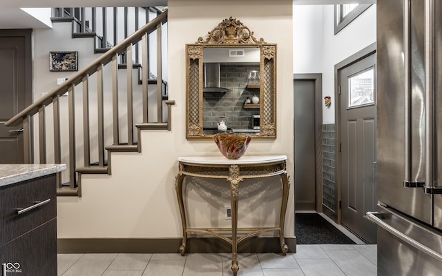 entryway with light tile patterned floors, visible vents, baseboards, and stairs