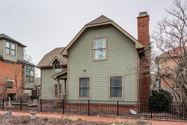 rear view of house with a fenced front yard and a chimney