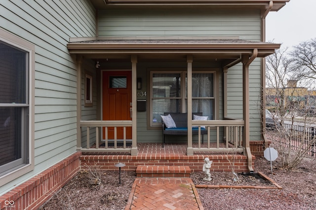 property entrance with a porch and fence