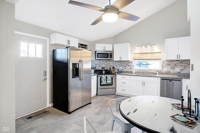 kitchen with vaulted ceiling, sink, stainless steel appliances, and white cabinetry