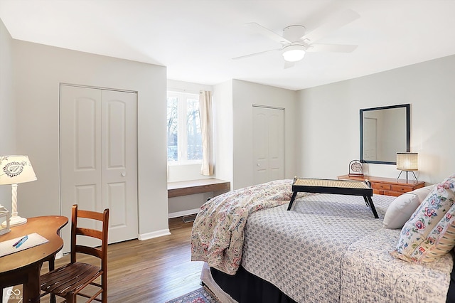 bedroom featuring ceiling fan, dark hardwood / wood-style floors, and multiple closets