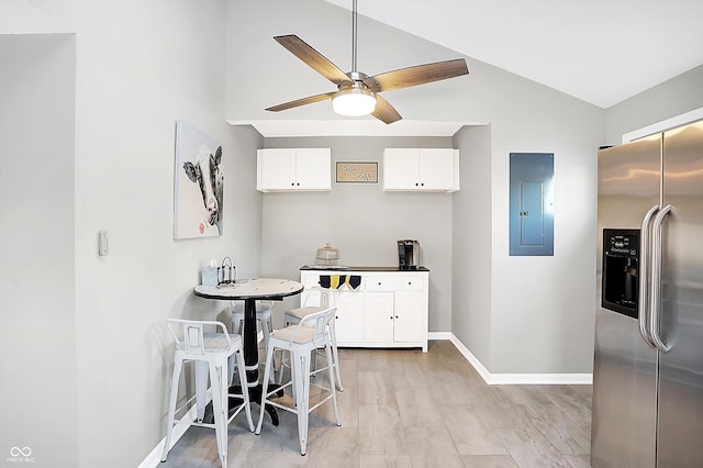 kitchen featuring lofted ceiling, ceiling fan, electric panel, stainless steel refrigerator with ice dispenser, and white cabinets