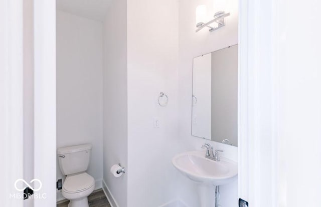 bathroom featuring toilet, wood-type flooring, and sink