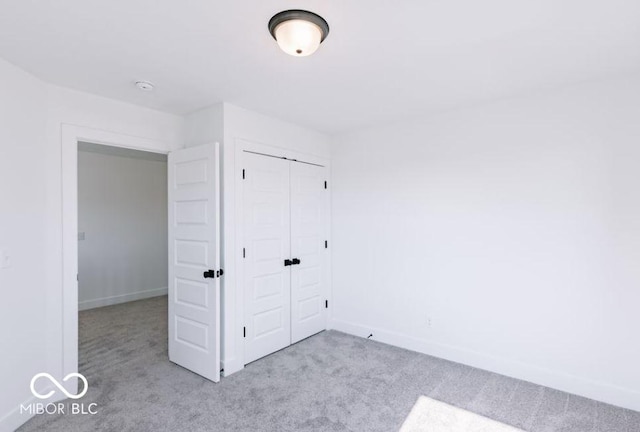 unfurnished bedroom featuring light carpet and a closet