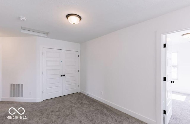 unfurnished bedroom featuring a closet and light colored carpet