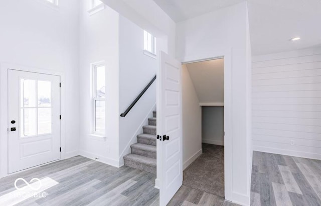 foyer entrance with a towering ceiling and light wood-type flooring