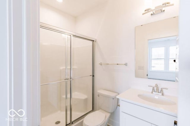 bathroom featuring a shower with shower door, vanity, and toilet