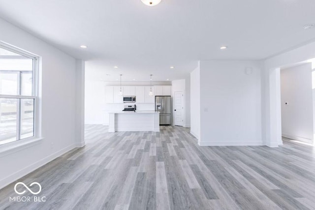 unfurnished living room with a healthy amount of sunlight and light wood-type flooring