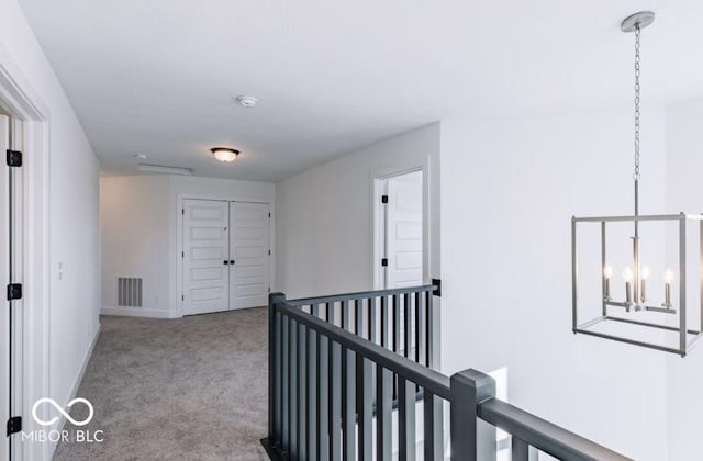 corridor featuring light colored carpet and a notable chandelier