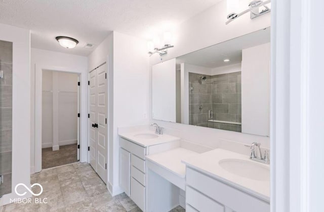 bathroom featuring a textured ceiling, a shower with door, and vanity