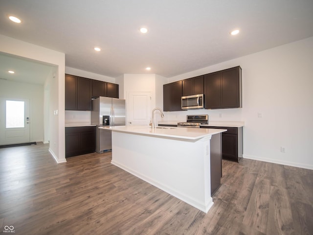 7824 Magnolia St, New Palestine, IN 46163 - kitchen with stainless steel appliances, dark wood finished floors, dark brown cabinets, light countertops, and a kitchen island with sink