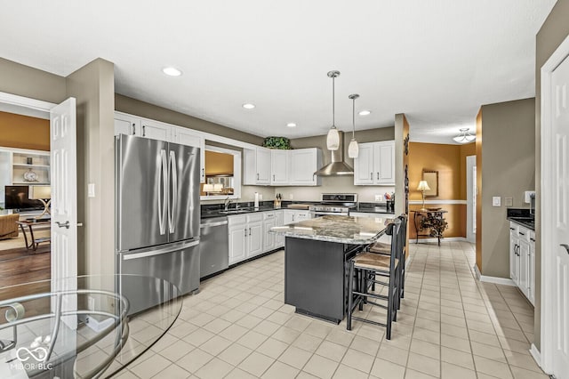 kitchen featuring sink, stainless steel appliances, a center island, white cabinets, and decorative light fixtures